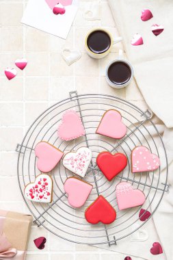 Composition with tasty heart shaped cookies and cups of coffee on light tile. Valentine's Day celebration