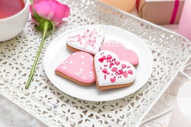 Tray with plate of tasty heart shaped cookies and rose flower on table, closeup. Valentine's Day celebration