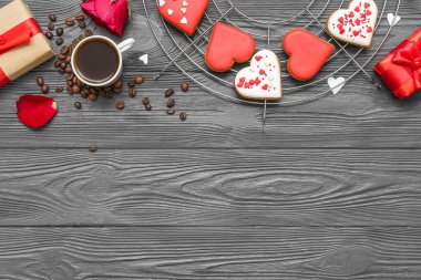 Composition with tasty heart shaped cookies, gift boxes and cup of coffee on dark wooden background. Valentine's Day celebration