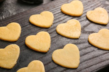 Wooden board with raw heart shaped cookies, closeup. Valentines Day celebration