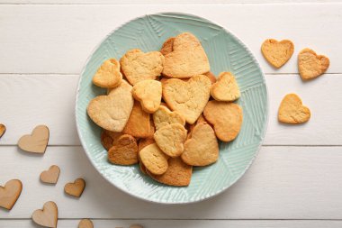 Plate with tasty heart shaped cookies on light wooden background. Valentines Day celebration