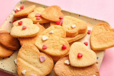 Plate with sweet heart shaped cookies and sprinkles on pink background, closeup. Valentines Day celebration
