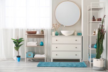 Interior of bathroom with sink on drawer, mirror and bath accessories