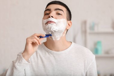 Morning of young man shaving in bathroom