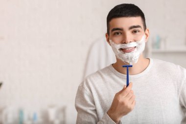 Morning of young man shaving in bathroom