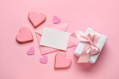 Composition with blank card, gift box and tasty cookies on pink background. Valentines Day celebration