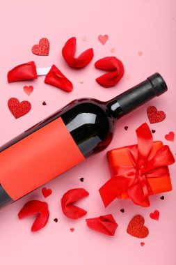 Fortune cookies with gift and bottle of wine on pink background. Valentine's Day celebration