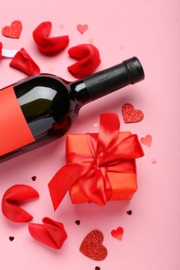 Fortune cookies with gift and bottle of wine on pink background. Valentine's Day celebration
