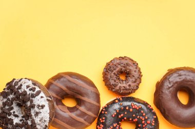 Different delicious donuts on yellow background