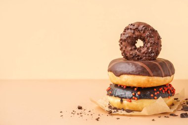 Parchment with delicious chocolate donuts on beige background