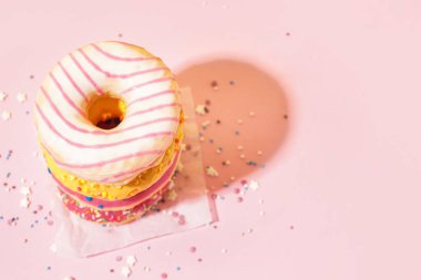 Parchment with different delicious donuts on pink background