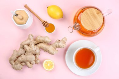 Ginger roots, cup of black tea, lemon and honey on pink background