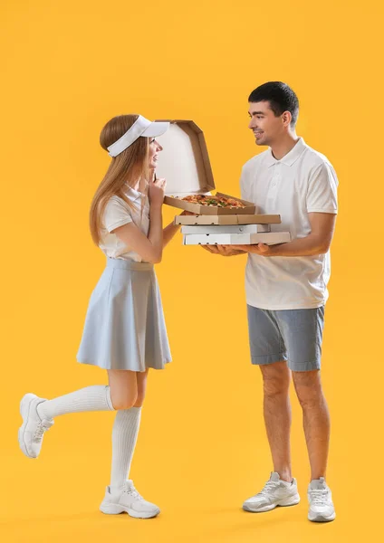 有一盒黄色背景的披萨的年轻夫妇 — 图库照片