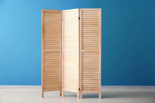 Wooden folding screen near blue wall