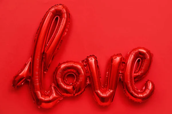 Foil balloon in shape of word LOVE on red background. Valentine\'s Day celebration