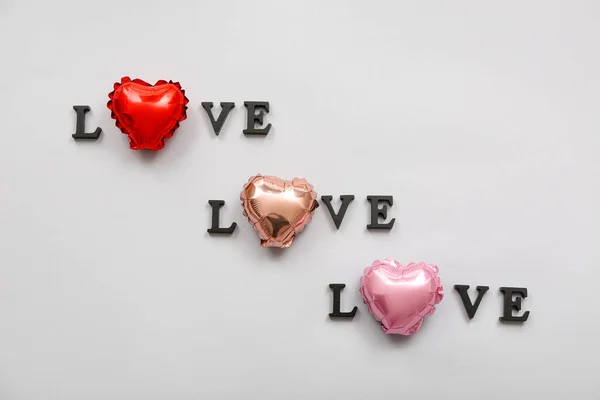 Words LOVE made of dark letters and foil balloons on light background. Valentine\'s Day celebration