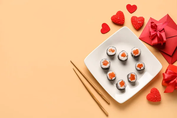 Plate with sushi rolls, chopsticks, gifts and envelopes on color background. Valentine\'s Day celebration