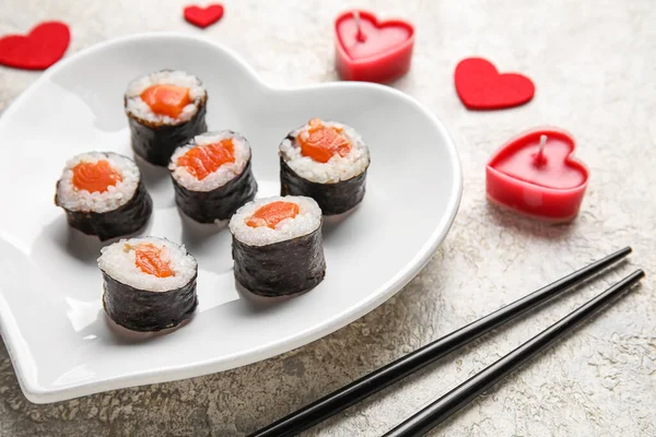 Plate with sushi rolls, chopsticks, hearts and candles on grunge background, closeup. Valentine\'s Day celebration