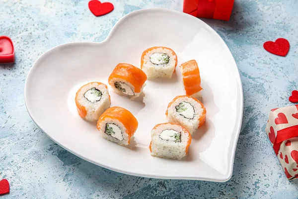 Plate with sushi rolls and hearts on grunge background, closeup. Valentine\'s Day celebration