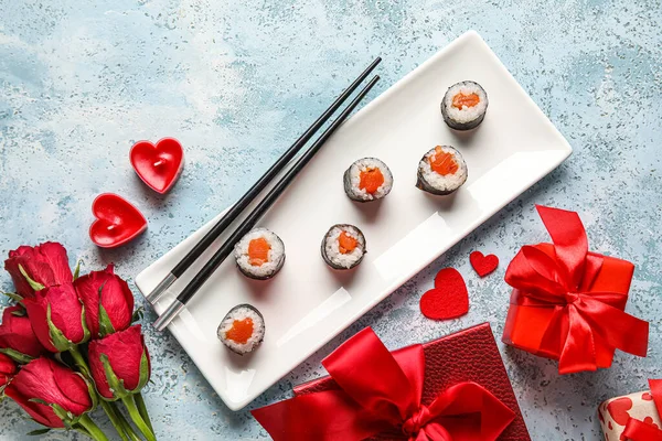 Plate with sushi rolls, roses and gifts on grunge background. Valentine\'s Day celebration