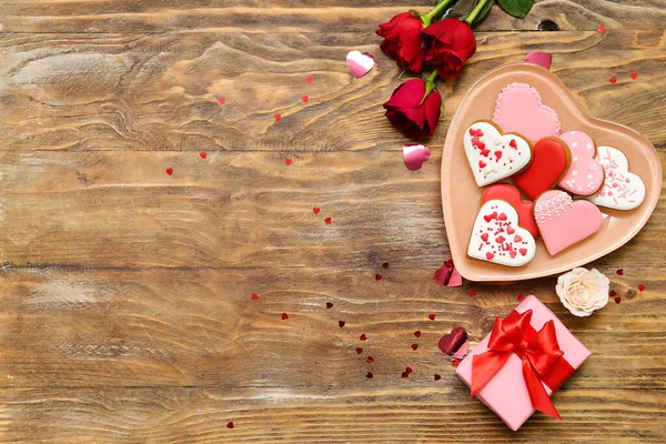 木製の背景においしいハート形のクッキー ギフトボックスとバラの花のプレートと構成 バレンタインデーのお祝い — ストック写真