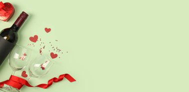 Bottle of wine, gift, glasses and hearts on green background with space for text. Valentine's Day Celebration