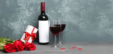 Glasses of wine, bottle, rose flowers and gift box on table. Valentine's Day banner