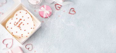 Box with heart-shaped bento cake and gifts on grunge background with space for text. Valentine's Day celebration