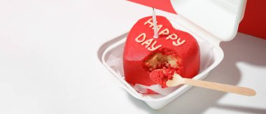 Plastic lunch box with tasty bento cake and candle on white table. Valentine's Day celebration