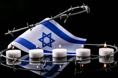 Burning candles, flag of Israel and barbed wire on dark background. International Holocaust Remembrance Day