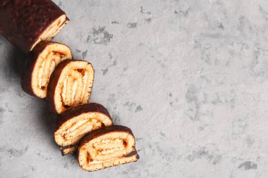 Pieces of tasty sponge cake roll on grunge background