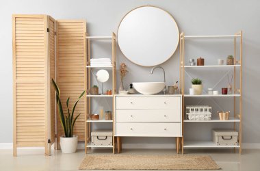Interior of bathroom with ceramic sink, drawers and shelving units