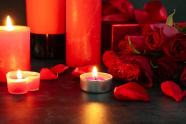Burning candles and beautiful rose flowers on dark background, closeup. Valentine's Day celebration