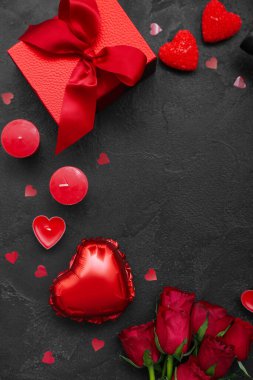 Composition with candles, gift box and rose flowers on dark background, closeup. Valentine's Day celebration