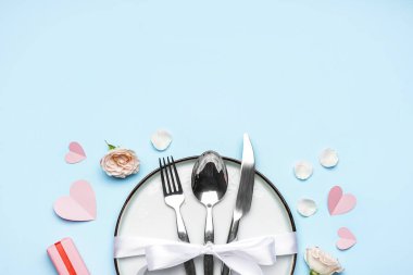 Table setting for Valentine's Day with rose and hearts on blue background