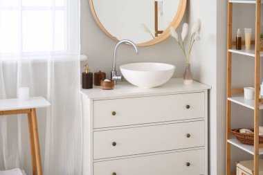 Interior of bathroom with sink on drawer, mirror and bath accessories