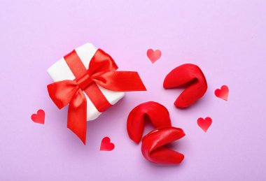 Composition with gift box and tasty fortune cookies on lilac background. Valentine's Day celebration