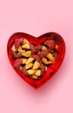 Heart-shaped gift box with fortune cookies on pink background. Valentine's Day celebration