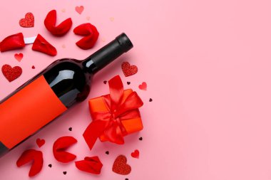 Fortune cookies with gift and bottle of wine on pink background. Valentine's Day celebration