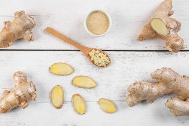 Fresh ginger, slices and spoon on wooden background