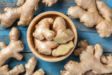 Bowl with ginger roots on wooden table, closeup