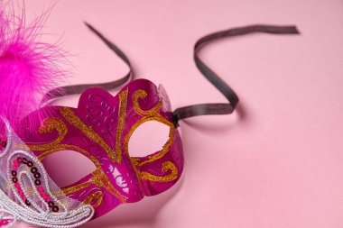 Beautiful carnival mask for Mardi Gras celebration on pink background, closeup