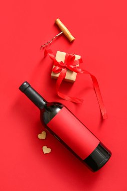 Bottle of wine, gift box and corkscrew on red background. Valentines Day celebration