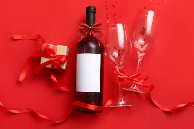Composition with bottle of wine, glasses and gift for Valentines Day on red background
