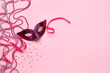 Carnival mask for Mardi Gras celebration with stars and beads on pink background