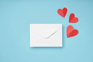 Envelope with paper hearts on blue background. Valentines Day celebration