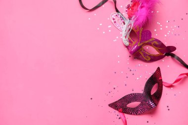 Carnival mask for Mardi Gras celebration with confetti and beads on pink background