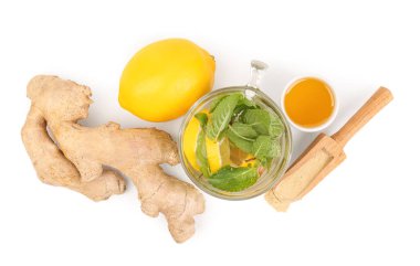 Glass of water with sliced ginger root, mint, and lemon isolated on white background