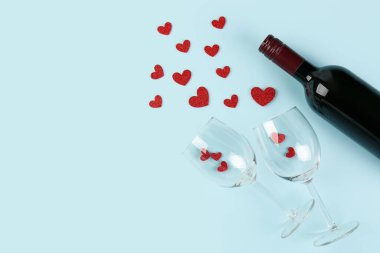 Bottle of wine, glasses and hearts on blue background. Valentines Day celebration