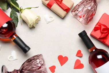 Frame made of bottles of wine, rose flower, glasses and hearts on white table. Valentine's Day celebration